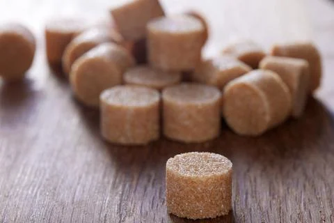 Brown round sugar forms on a old dark wooden cutting board Foto stock