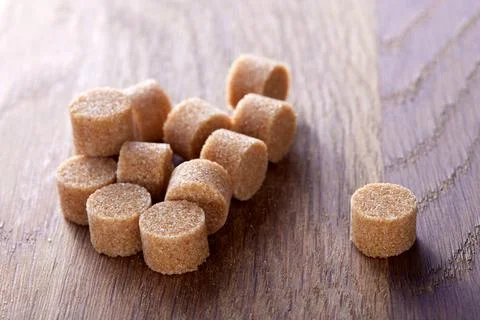 Brown round sugar forms on a old dark wooden cutting board 写真素材