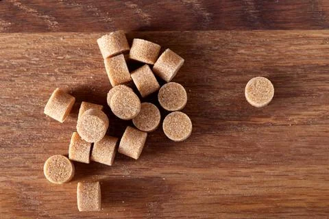 Brown round sugar forms on a old dark wooden cutting board 写真素材
