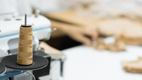 Brown sewing thread skein on spool with blurred fabric background Stock Photos