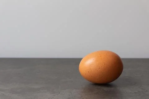 Brown single large egg over grey table on white background. Stock Photos