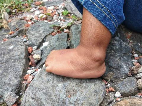 Brown skin toddler feet standing on rock in outdoors Stock Photos