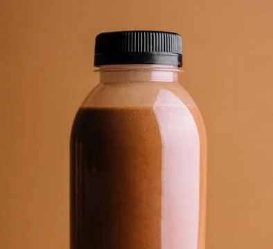 Brown smoothies in a bottle on a brown background Stock Photos