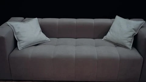 A brown sofa with medium beige cushions, shot in slow motion against a black Video stock 232056185