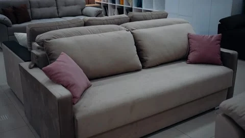 Brown sofa with red cushions set up in a furniture store. 4k video. Stock Footage 231689132