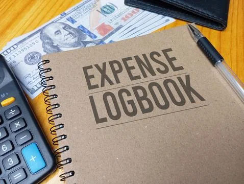 Brown spiral notebook with Expense Logbook text on a wooden desk with a cal.. Stock Photos
