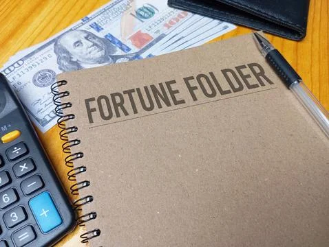 Brown spiral notebook with FORTUNE FOLDER text on a wooden desk with a calc.. Stock Photos
