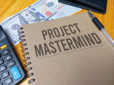Brown spiral notebook with Project Mastermind text on a wooden desk with a .. Stock Photos