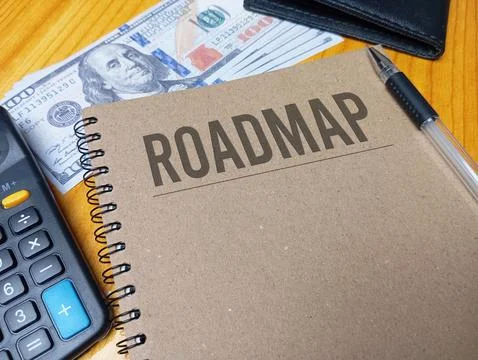 Brown spiral notebook with ROADMAP text on a wooden desk with a calculator .. Stock Photos