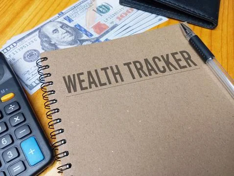 Brown spiral notebook with Wealth Tracker text on a wooden desk with a calc.. Stock Photos