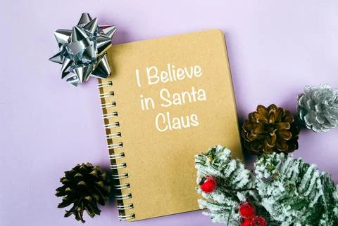 Brown spiral notebook with the words I believe in Santa Claus written on it Stock Photos