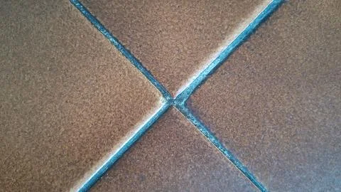 Brown square ceramic floor tiles with dark grey grout lines detail Stock Photos