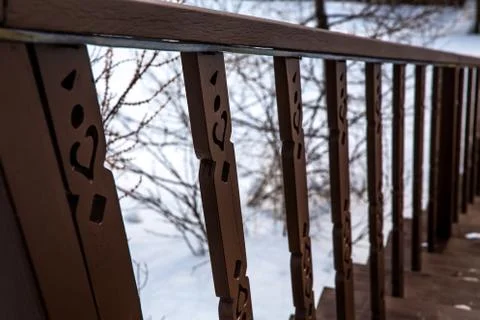 Brown staircase railing in winter against a background of tree branches Stock Photos