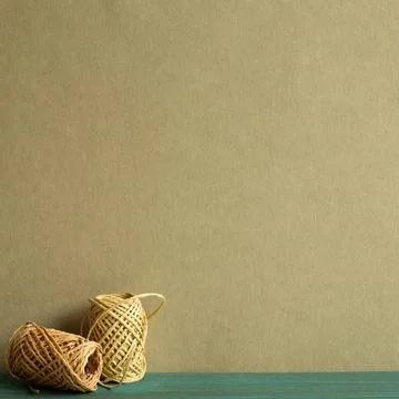 Brown string thread reel on wooden desk with khaki green background Stockfoto's