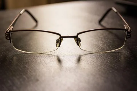 Brown Stylish Reading Glasses Setting on Black Desktop Workspace Empty Quiet Stock Photos