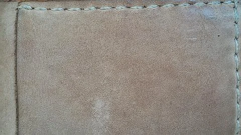 Brown suede leather texture background featuring delicate light colored hand Stock Photos