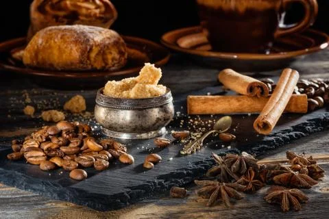 Brown sugar, coffee grains and sticks of cinnamon on a black plate from slate Stock Photos