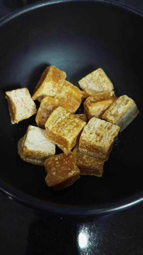 Brown sugar cubes filling a dark bowl, offering natural sweetness for cooking, Stock Footage 345515343