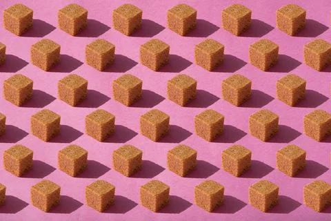 Brown sugar cubes pattern on pink background. Abstract, minimal style. Stock Photos