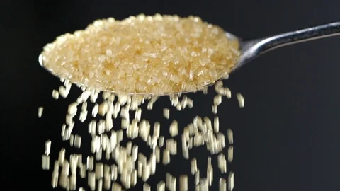 Brown sugar falling from tea spoon in slow motion Vídeo Stock 115631519