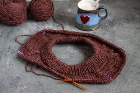 Brown sweater, knitting process, with ceramic cup on concrete background Stock Photos