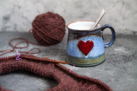 Brown sweater, knitting process, with ceramic cup on concrete background Stock Photos