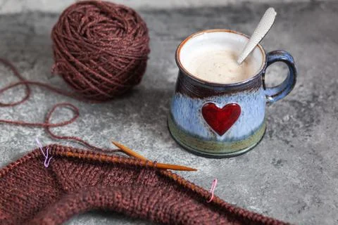Brown sweater, knitting process, with ceramic cup on concrete background Stock-Fotos