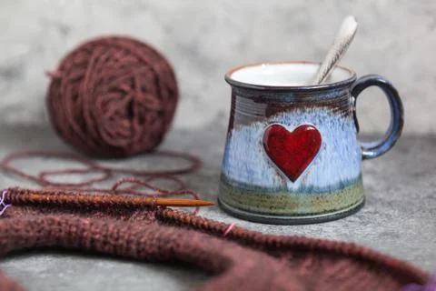 Brown sweater, knitting process, with ceramic cup on concrete background Stock Photos
