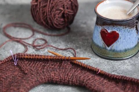 Brown sweater, knitting process, with ceramic cup on concrete background Stock Photos
