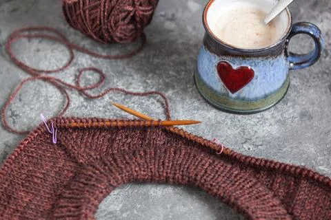 Brown sweater, knitting process, with ceramic cup on concrete background Foto stock