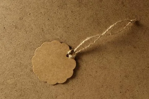Brown tag on a plain surface with string for gift labeling or decoration Stock Photos