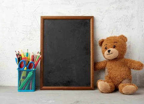 Brown teddy bear and empty wooden rectangular frame, chalk board for writing  写真素材