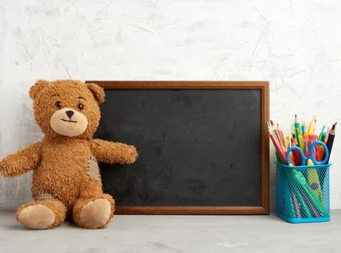 Brown teddy bear and empty wooden rectangular frame, chalk board for writing  Stock Photos