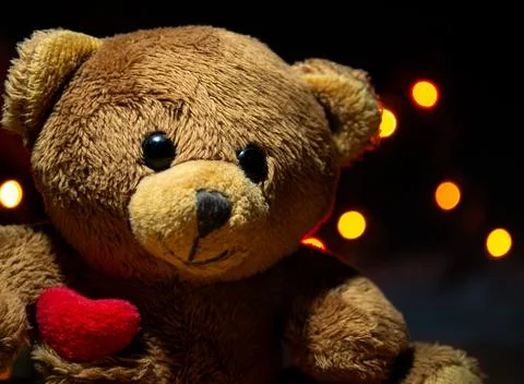 Brown teddy bear close up on the background of garland lights in bokeh Stock Photos