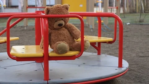 Brown Teddy Bear on a Rotating Childrens Carousel in Playground Stock Footage 154048097