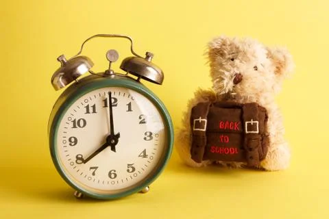 Brown teddy bear with school backpack, yellow background 库存照片