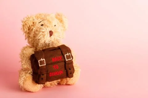 Brown teddy bear with school backpack, pink background Stock-Fotos