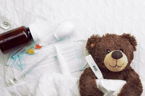 Brown teddy bear with a thermometer tablets and a medical mask Stock Photos