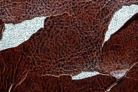 Brown textured leather material with irregular torn edges and visible fabric 스톡 사진