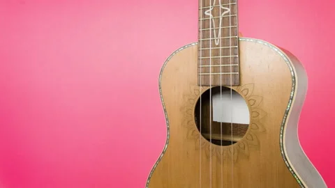 Brown ukulele - isolated on red background. Close up rotation art concept. Stock Footage 108650438
