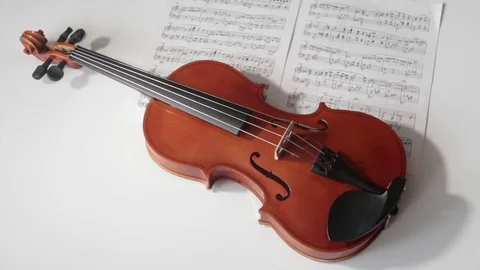 Brown violin with musical notes on a white background (spinning and panning Stock Footage 73893310