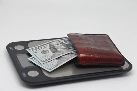 Brown wallet with banknotes on electronic kitchen scales. Symbol of accountin Stock Photos