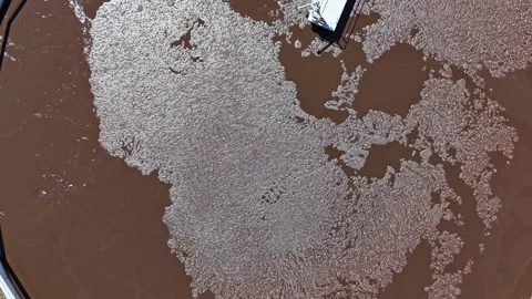 Brown water flows in patterns near structures on a sunny day in a coastal area, Stock Footage 339492315