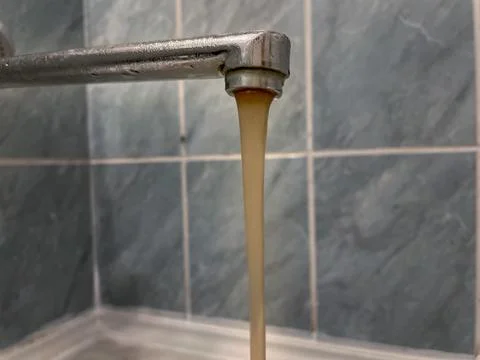 Brown water flows from the tap. Rusty water, bad water flows from the tap. Stock Photos