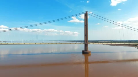 Brown water reflects sky and bridge tower Видео 343534598
