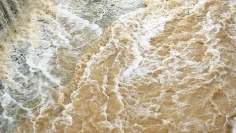 The brown water was flowing fast and was splashing violently Stock Footage 165914964