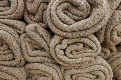Brown wool blankets rolled roll lie on the shelf. Texture of a warm plaid clo Stock Photos