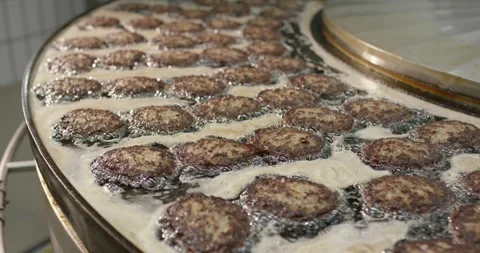 Browned patties crowd the bubbling fat of a round steel fryer, Overhead View Stock Footage 340043968