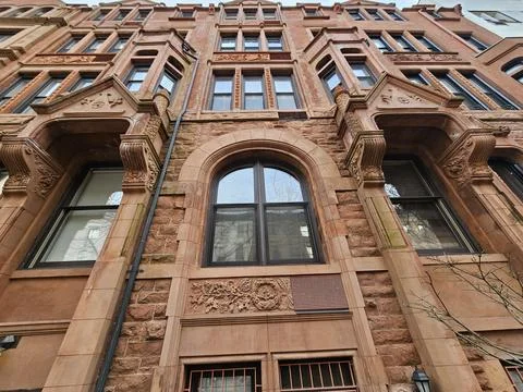Brownstone building facade with arched window and carved stone details Stock Photos
