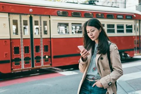 Browsing phone and standing while train passing 库存照片